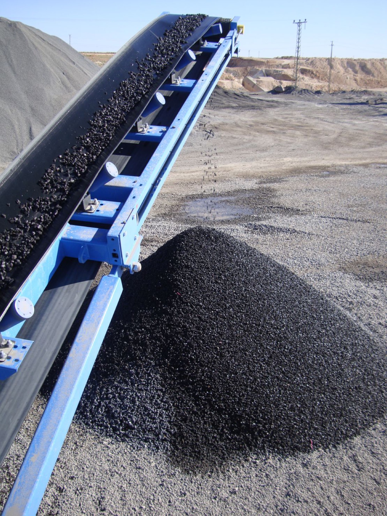 Conveyor dropping washed dark aggregate onto a conical heap
